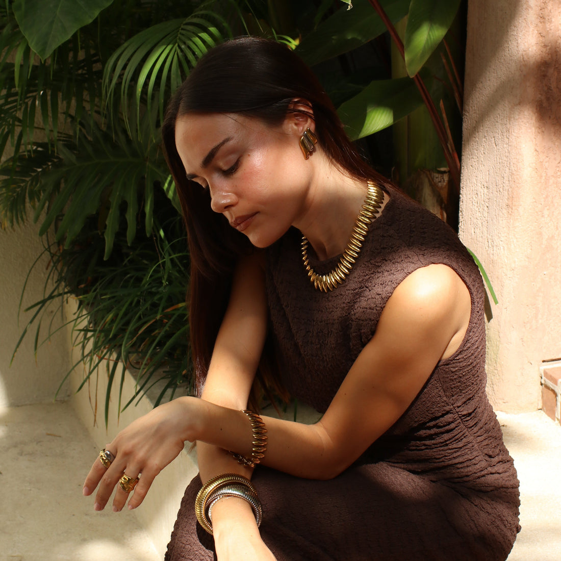 Femme portant un collier, des bracelets et des bagues en acier inoxydable 304 à finition dorée, Rélia Bijoux